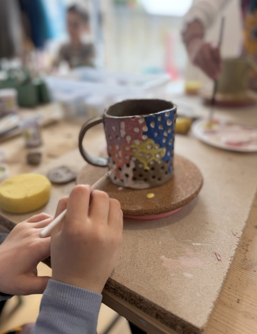 Kind bemalt eine bunte Tasse
